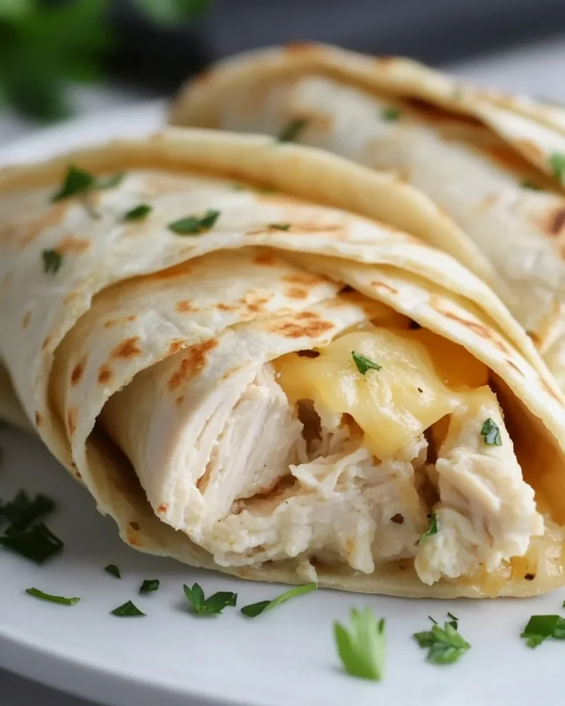 Cheesy Garlic Chicken Wraps Cheesy garlic chicken wraps served with fresh vegetables and sauce.